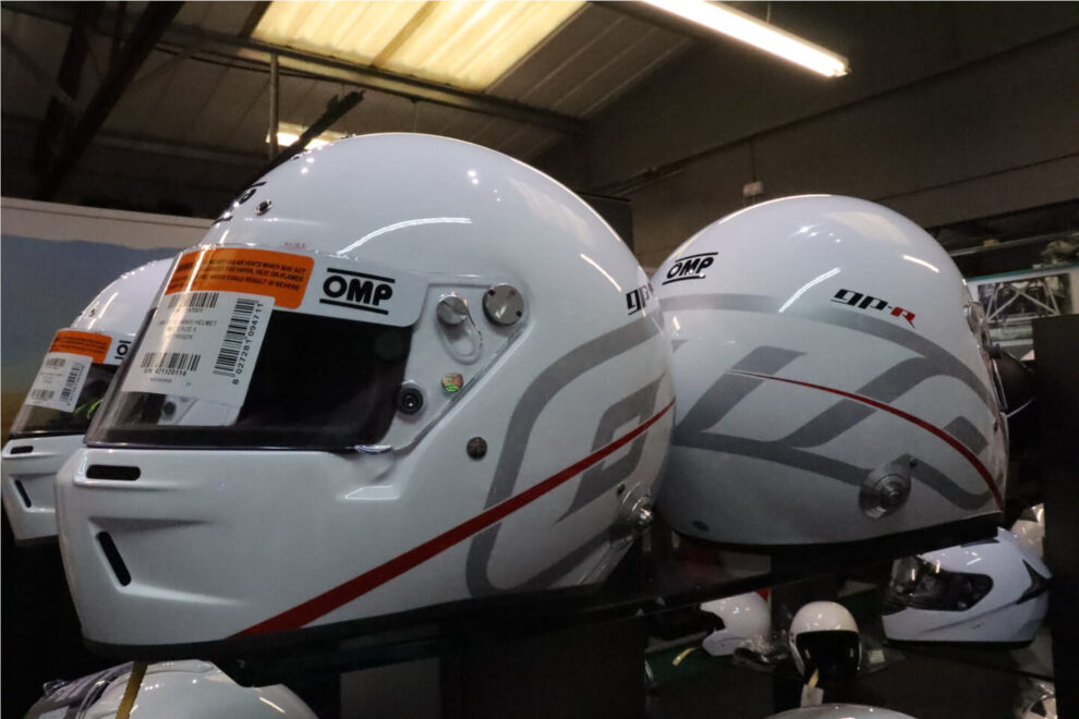 Close view of white OMP GP-R helmets side by side on the showroom shelf, showing the vents and grey graphics