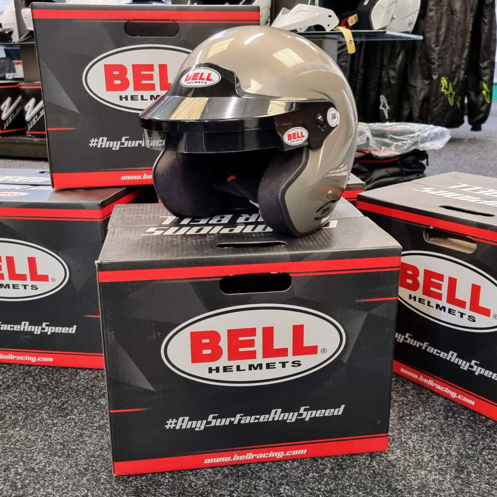 A titanium silver Bell Mag open face helmet sitting on stacked Bell helmet boxes in the GSM Performance showroom