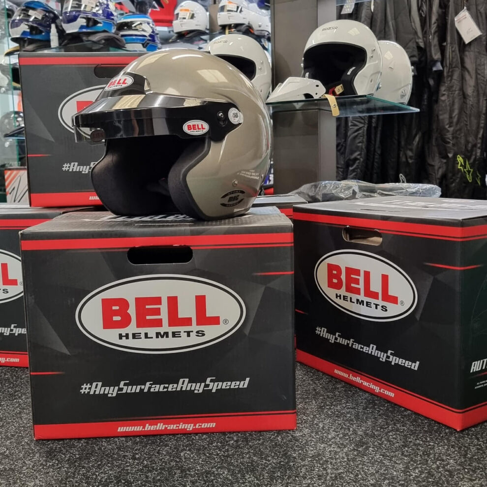 A grey Bell Mag open face helmet with a dark sunscreen sitting on Bell boxes in the GSM Performance showroom