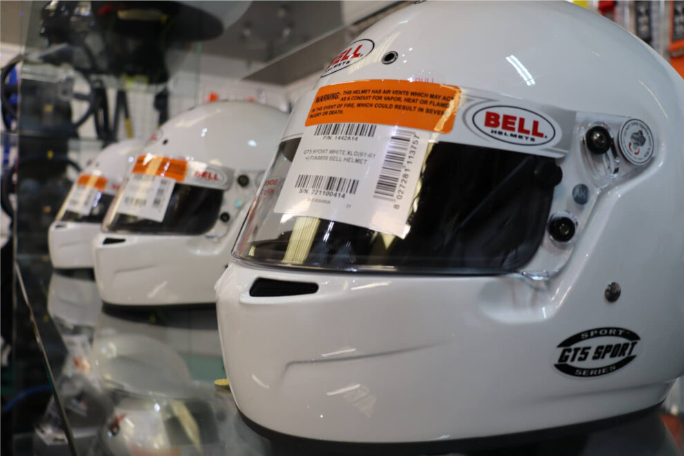 A row of white Bell GT5 Sport helmets on a glass shelf in the GSM Performance showroom
