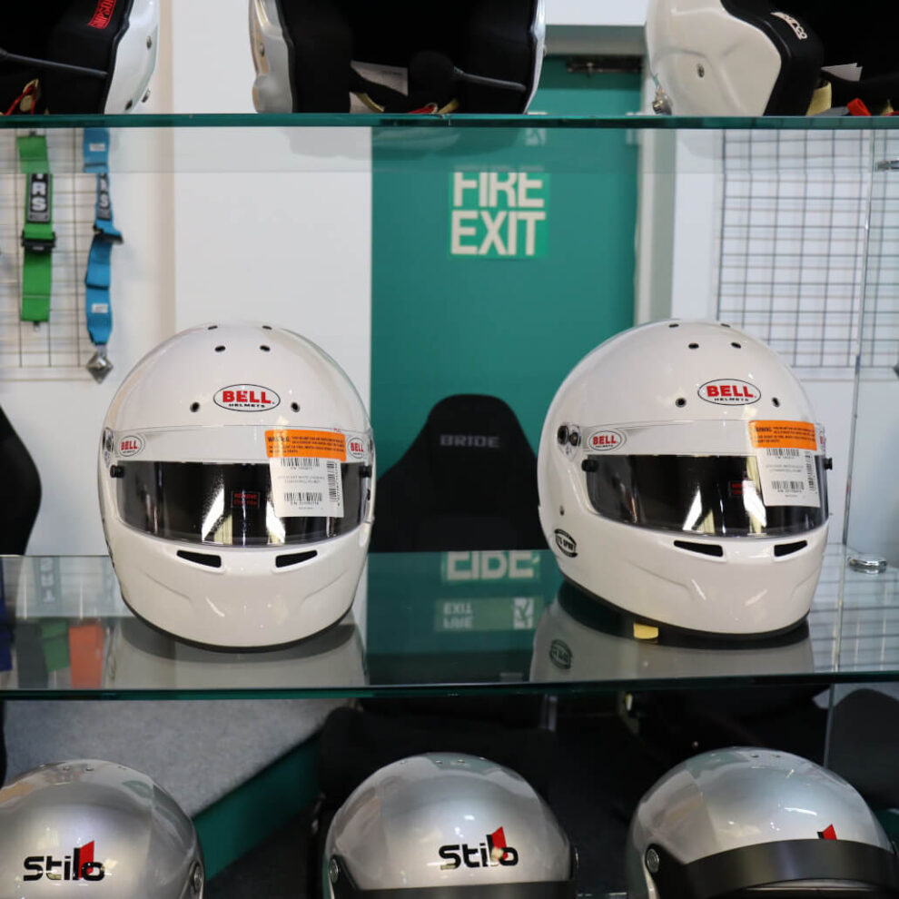Two white Bell helmets on a glass shelf with Stilo helmets on the shelf below