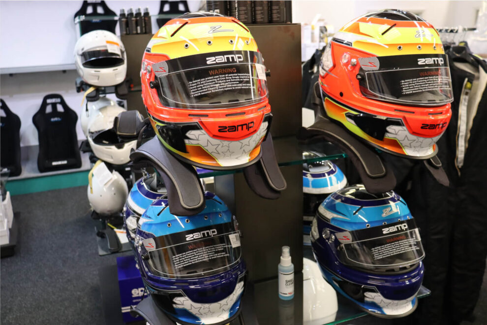 Orange and yellow and blue Zamp RZ-70E Switch helmets on a display stand in the GSM Performance showroom