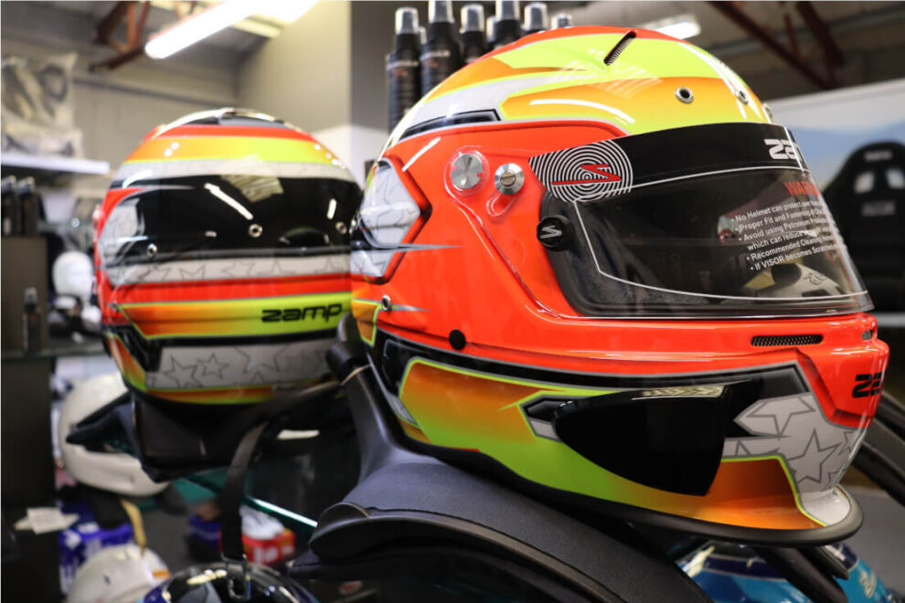 Close up of an orange and yellow Zamp RZ-70E Switch helmet with its visor, on a display stand