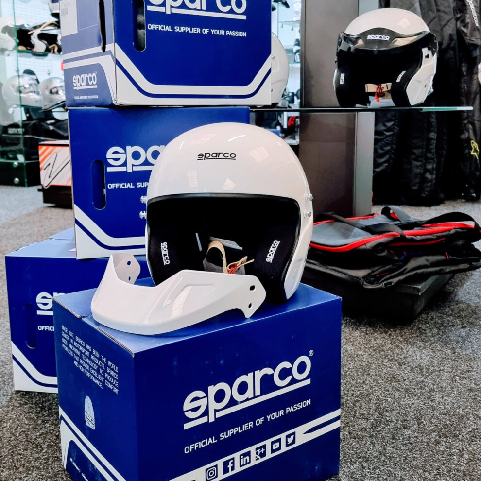 A white Sparco RJ helmet on a Sparco box, seen from the side, in the GSM Performance showroom