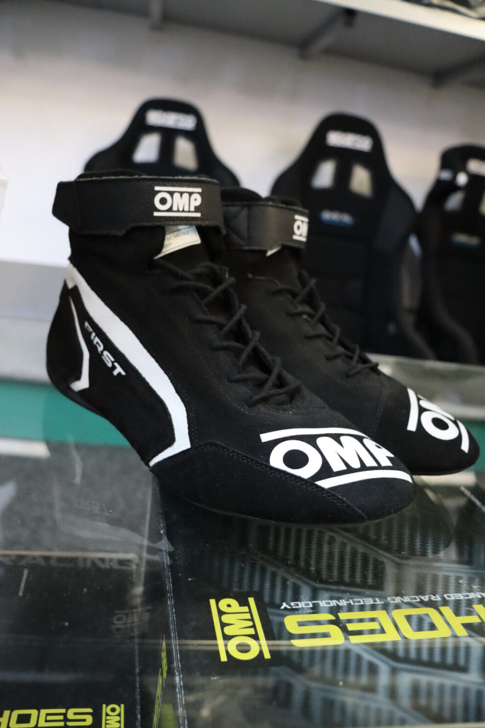 Black OMP First race boot with white detailing and a Velcro strap on a glass shelf