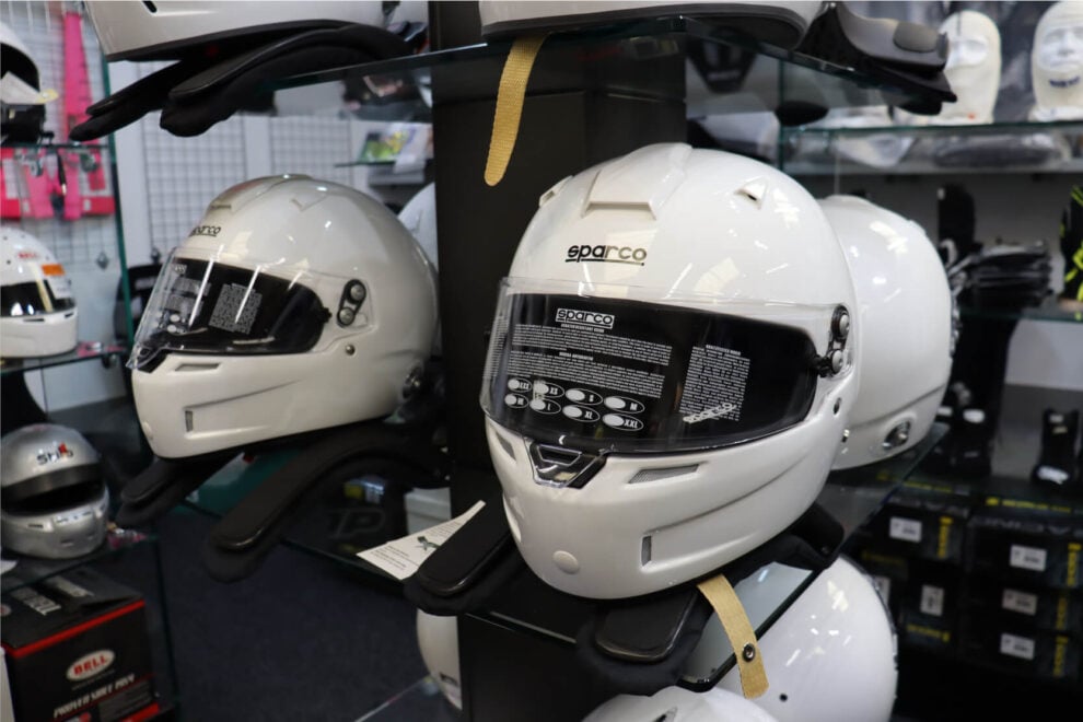 White Sparco full face helmet with a tinted visor on a HANS device on the GSM Performance showroom display