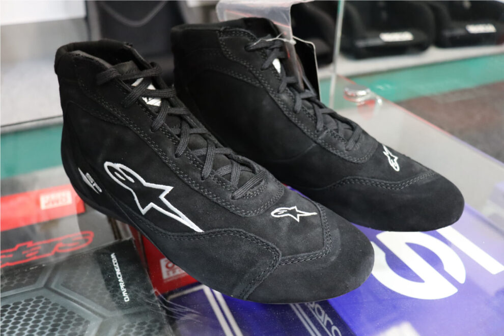 A pair of black suede Alpinestars SP V2 race boots on a glass shelf in the showroom