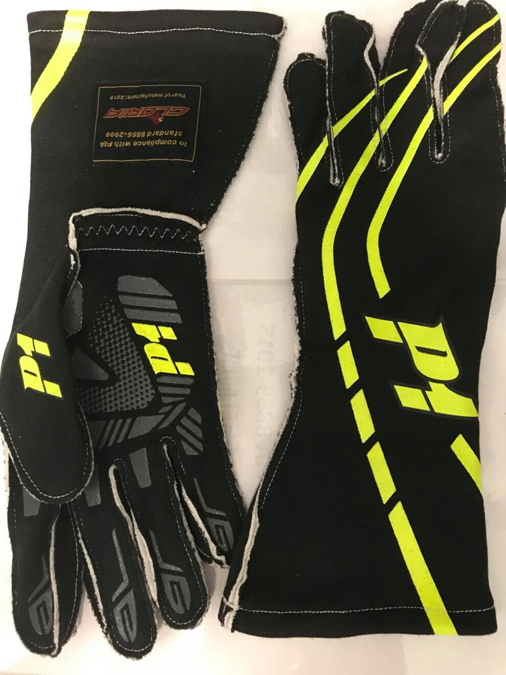 A pair of black P1 racing gloves with fluorescent yellow stripes and grip patterns on the palm