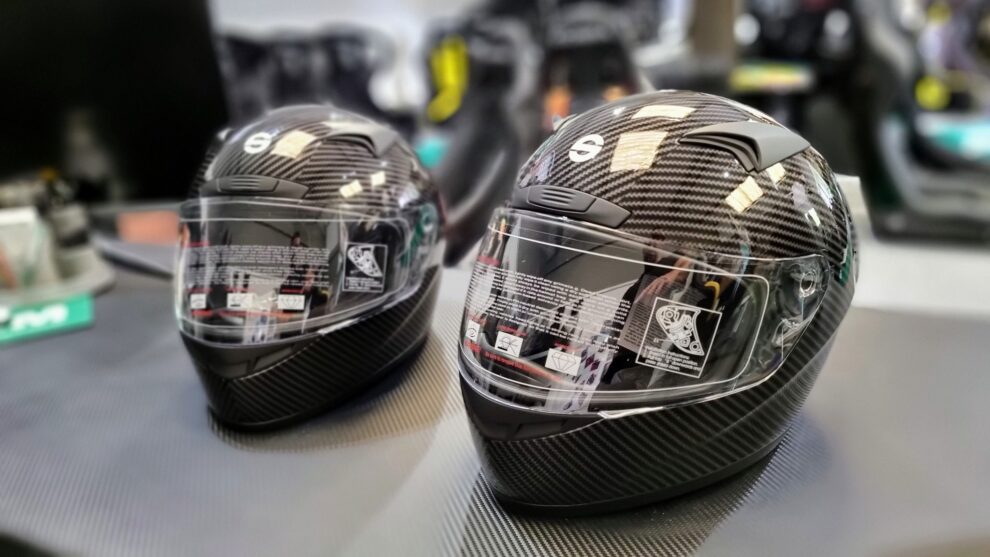 Two Sparco Club X1 Carbon full face helmets on a counter in the GSM Performance showroom, showing the carbon finish