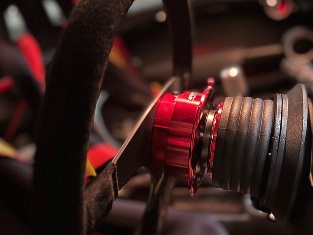 A red quick release steering wheel boss behind the OMP Velocita Superleggero in the customer's car