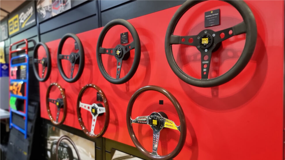 A red wall of MOMO steering wheels, leather and wood rimmed, on the MOMO stand at Autosport International 2023