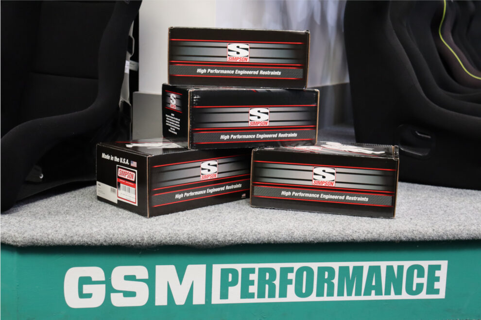 Four boxed Simpson head and neck restraints stacked on the GSM Performance display plinth