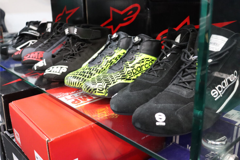 Sparco K-Formula kart boots on a glass shelf alongside OMP and Sparco race boots in the GSM Performance showroom