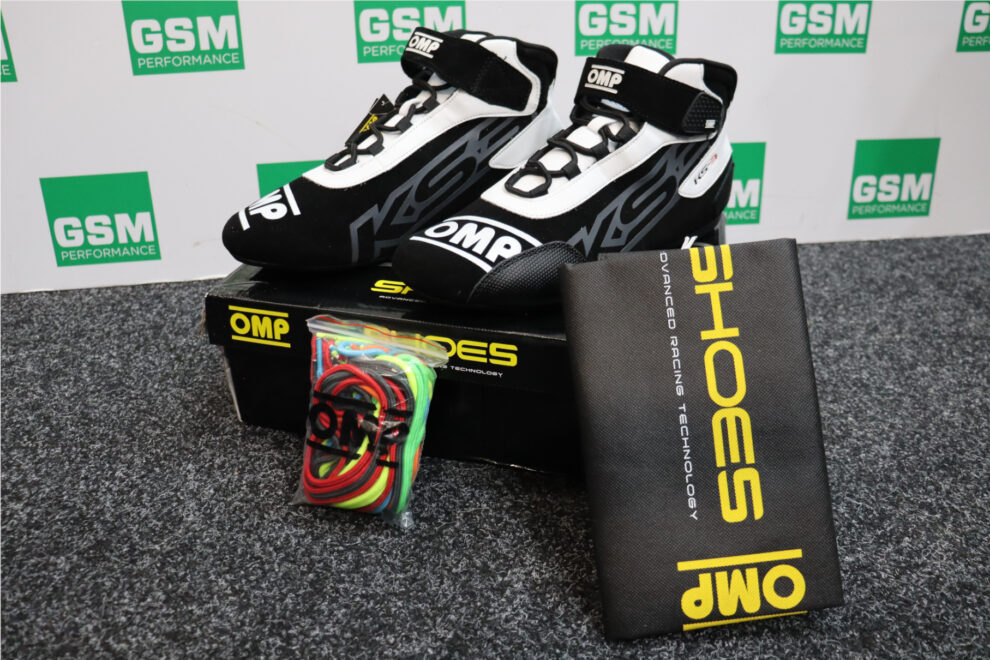 OMP KS-3 kart boots on their box with a bag of coloured spare laces and a black OMP shoe bag, in front of a GSM Performance banner