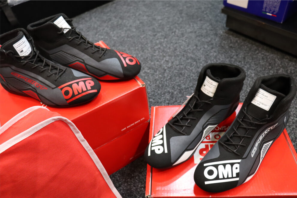Close view of OMP Sport race boots in black and red and in black and white, sitting on OMP boxes