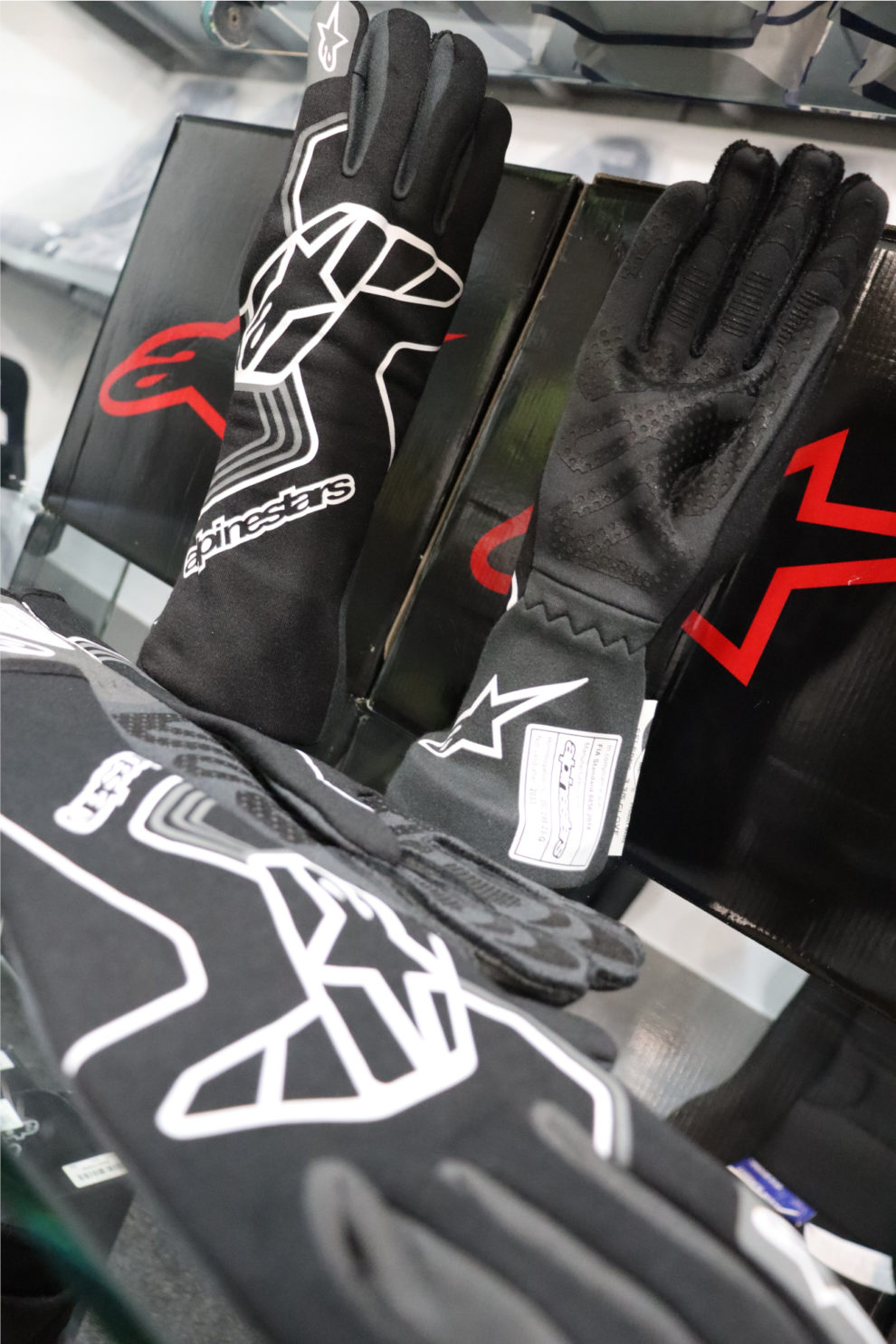 Close view of black Alpinestars Tech 1 Race V4 gloves, one showing the grey silicone palm print, on the showroom display