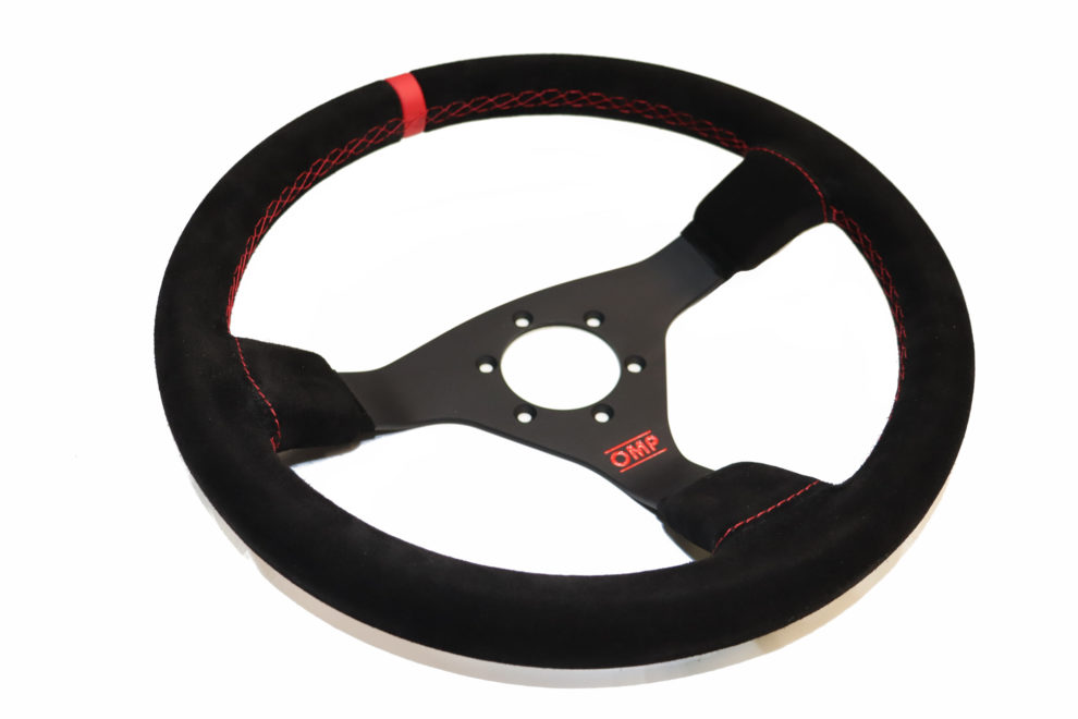 The OMP WRC steering wheel in black suede with red cross stitching and a red centre stripe, on a white background