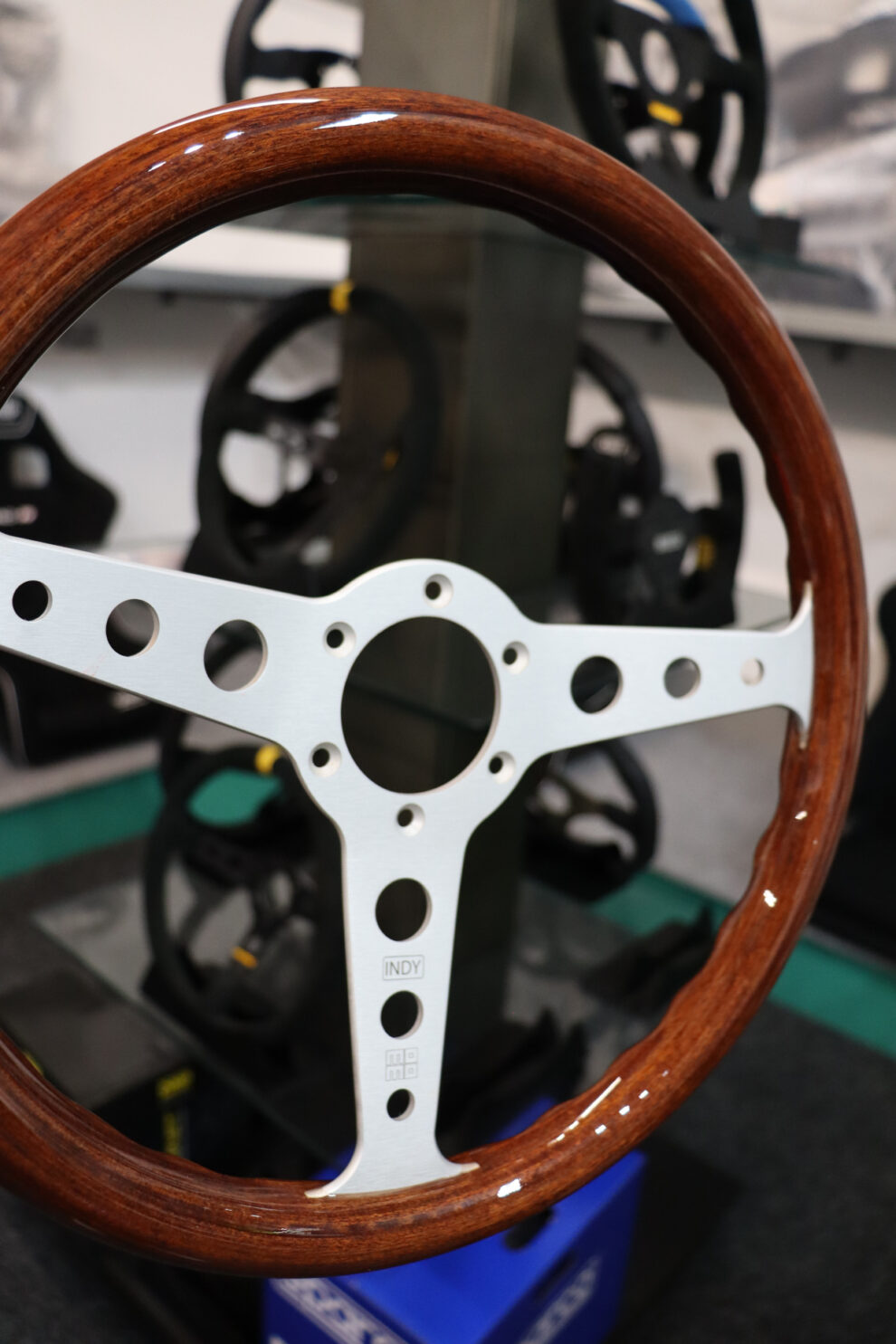 The MOMO Indy Heritage steering wheel on a stand in front of a display of black steering wheels in the GSM Performance showroom