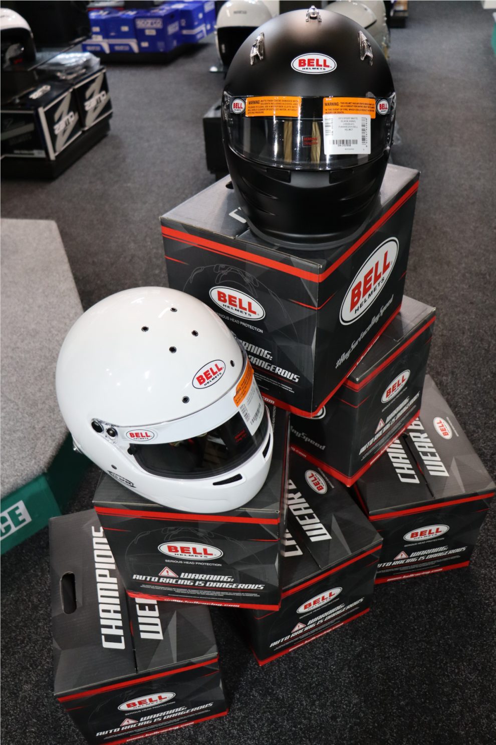A matt black Bell GP3 Sport helmet on a Bell box above a white Bell helmet on a second box, in the GSM Performance showroom