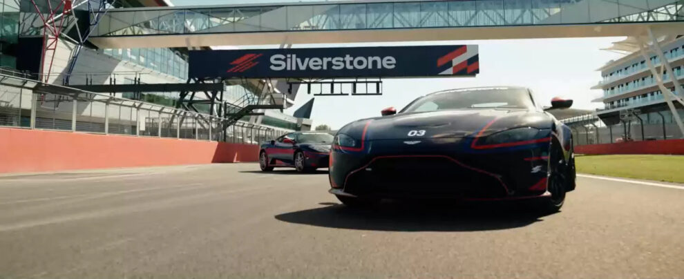 Two Aston Martin Vantage experience cars on the start straight at Silverstone under the Silverstone gantry