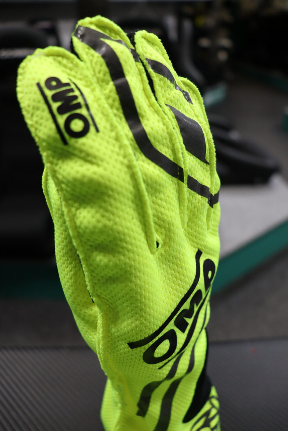 Close-up of the back of a fluorescent yellow OMP KS-X kart glove with black OMP logos