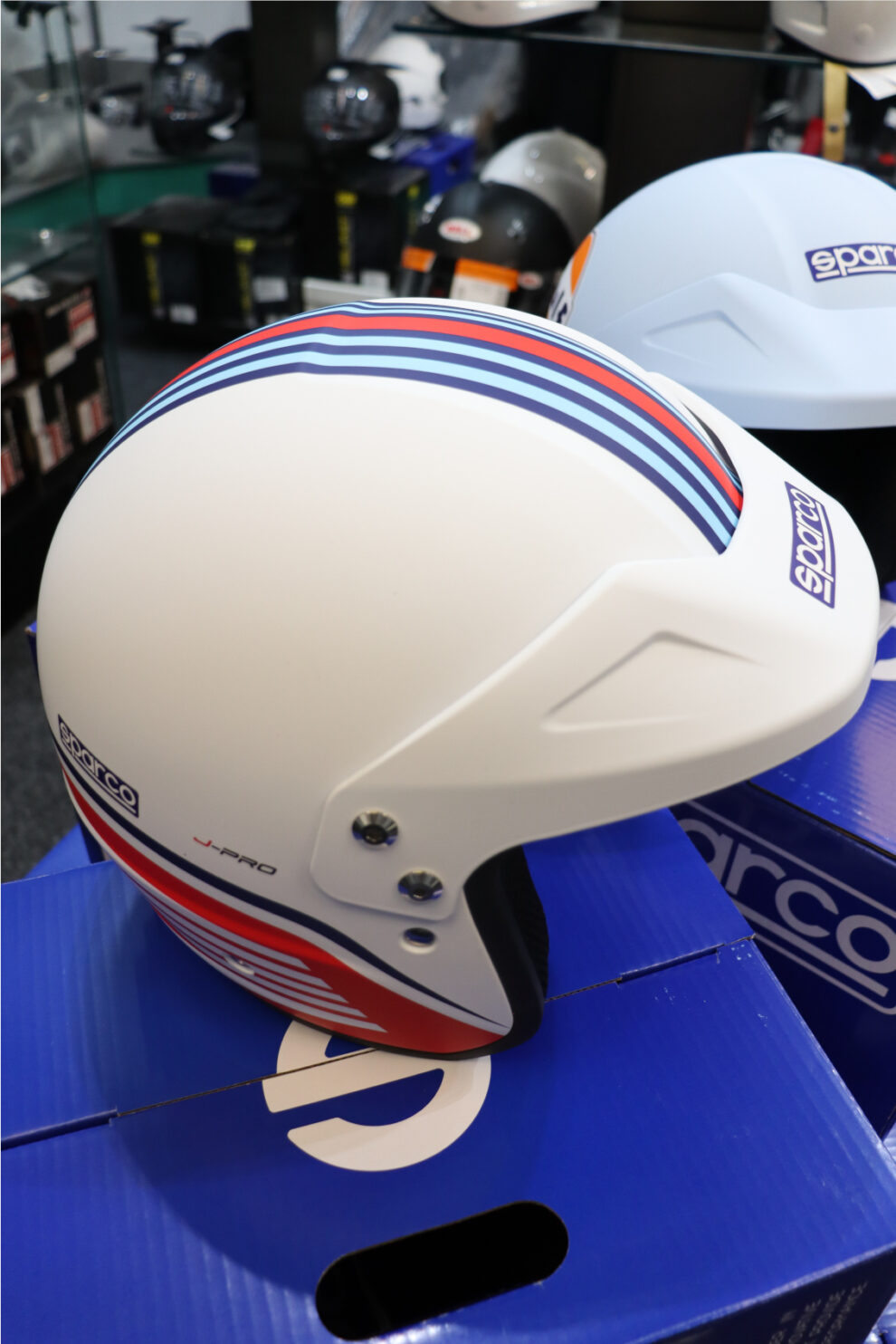 Side view of the white Sparco Martini Racing J-Pro helmet with light blue, navy and red stripes and the J-Pro logo