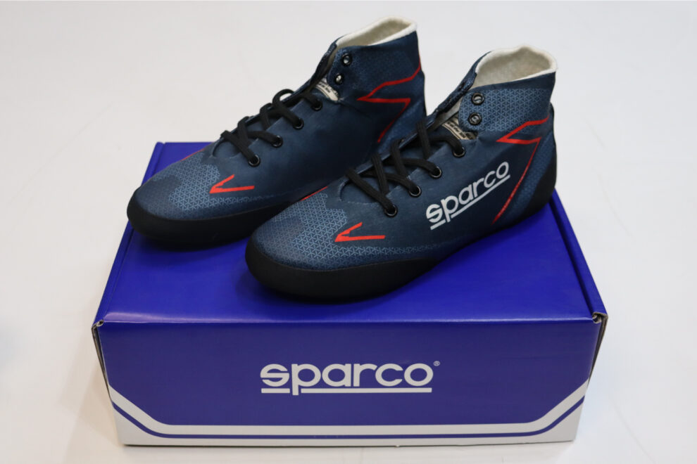 A pair of navy Sparco Prime Extreme race boots with red detailing standing on a blue Sparco box