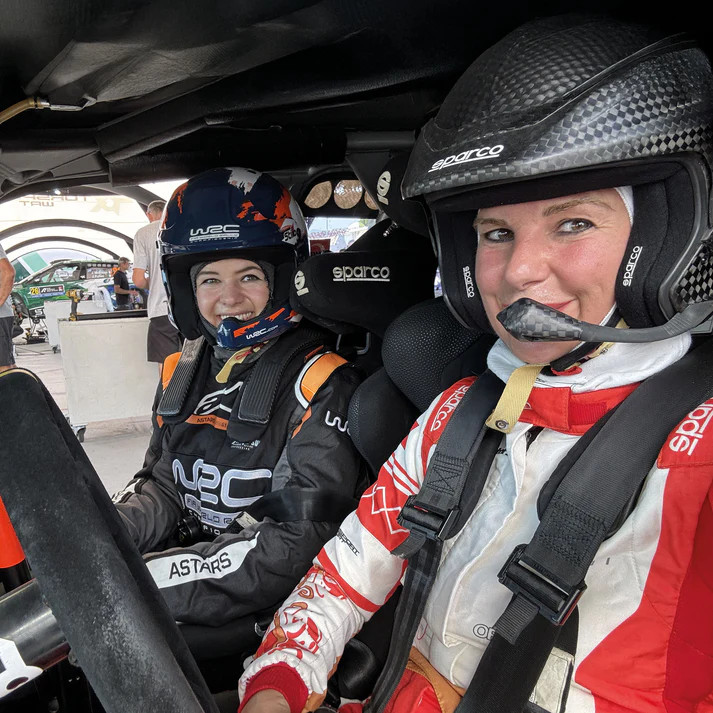 Two crew members in a rally car, one wearing a carbon Sparco open-face helmet with a boom microphone