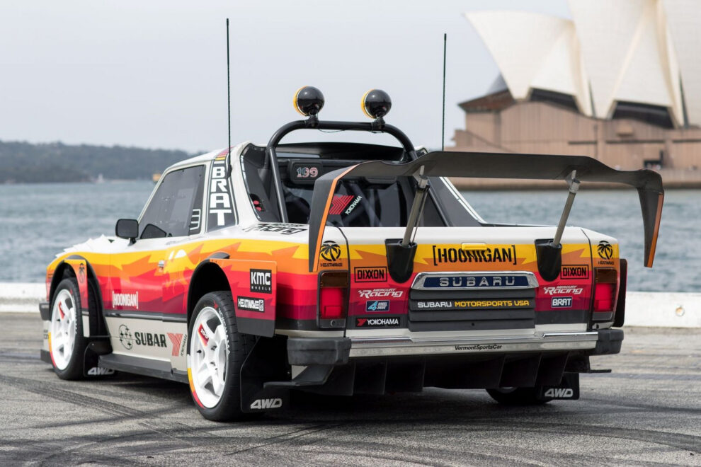 The rear of the Subaru Brataroo 9500 Turbo with its large rear wing, roll bar lights and Hoonigan livery, parked on a harbour quay with the Sydney Opera House behind