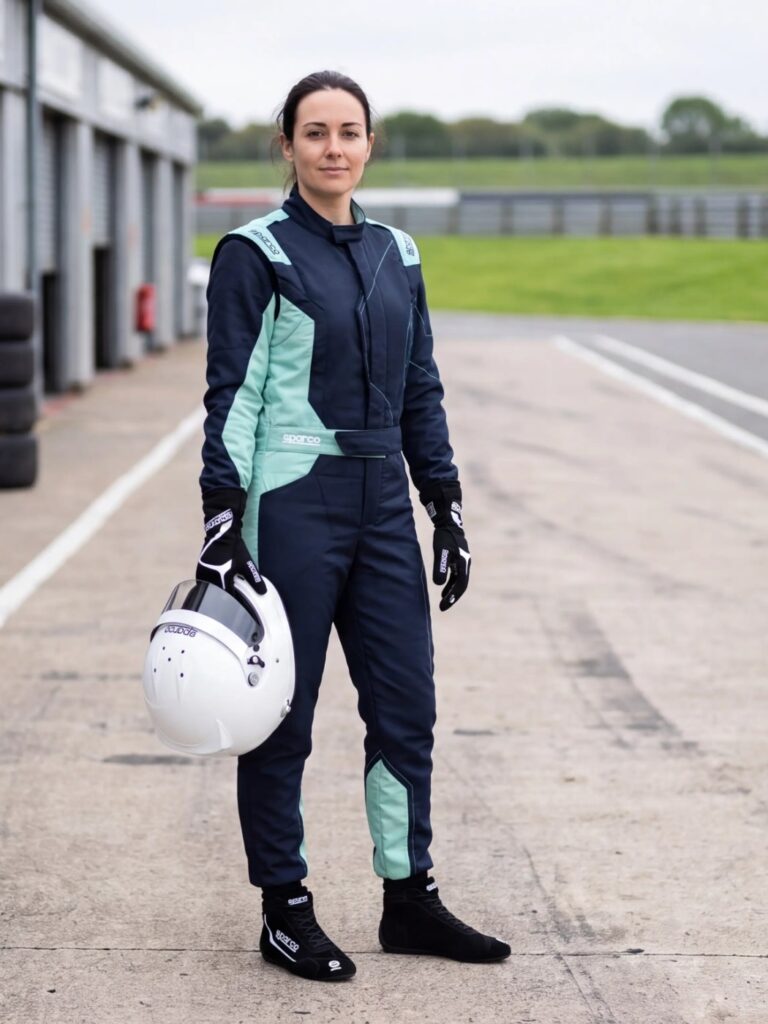 Driver wearing the Sparco Sprint Advanced race suit in Navy Blue and Mint Green with Sparco Slalom boots and Land gloves in Black, in a UK circuit pit lane