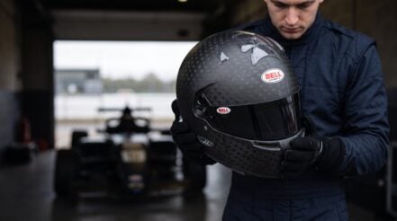 Driver holding a Bell HP77 Evo IV carbon helmet in a pit garage - GSM Performance
