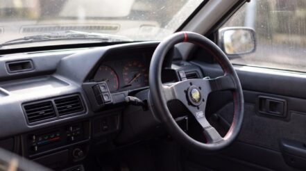 Interior of a right-hand-drive Daihatsu Charade with an OMP steering wheel fitted on an aftermarket boss kit — AI illustration generated from GSM Performance product photography