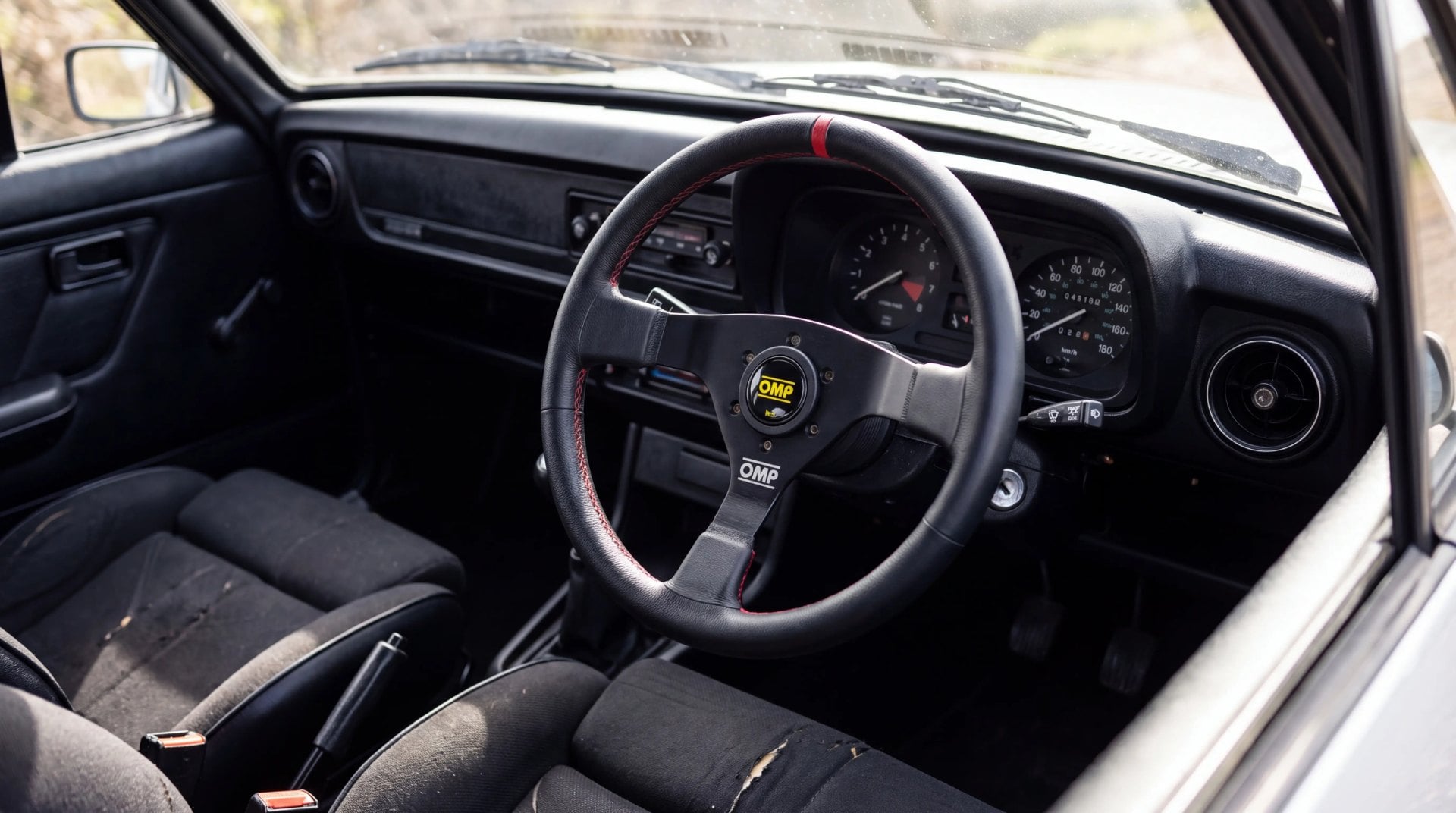 Right hand drive Ford Escort Mk2 cabin with a three spoke OMP steering wheel fitted to a boss kit