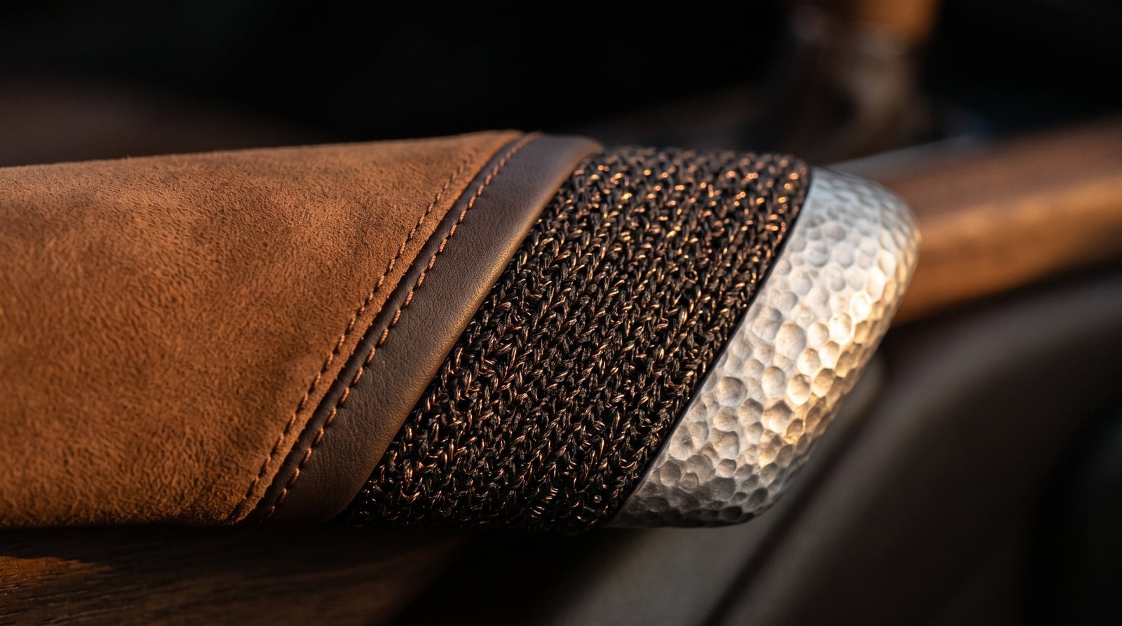 Macro of hammered aluminium trim beside brown nubuck and copper-threaded knit fabric