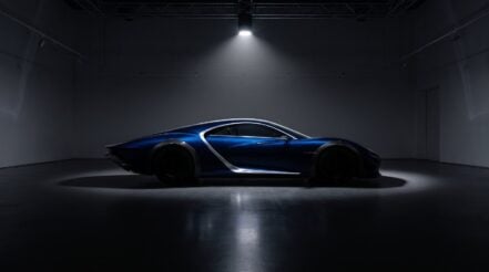 Low sculptural blue hypercar under a single gallery spotlight