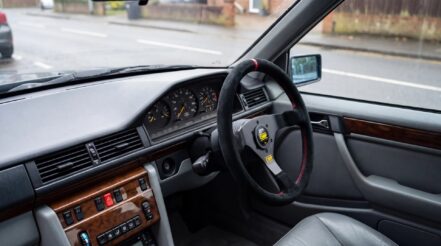 Black suede OMP steering wheel on a boss kit in the right hand drive cabin of a Mercedes W124 E Class