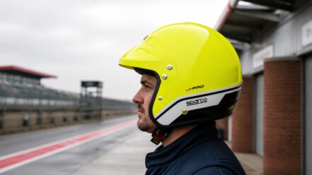 Driver in a pit lane wearing the fluorescent-yellow Sparco J-Pro open-face helmet