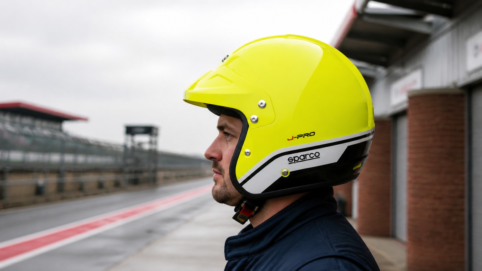 Driver in a pit lane wearing the fluorescent-yellow Sparco J-Pro open-face helmet