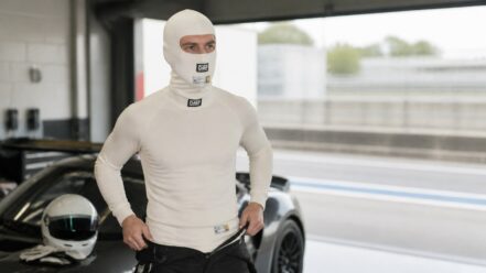 Racing driver wearing an OMP First FIA fireproof base-layer top and balaclava in a pit garage