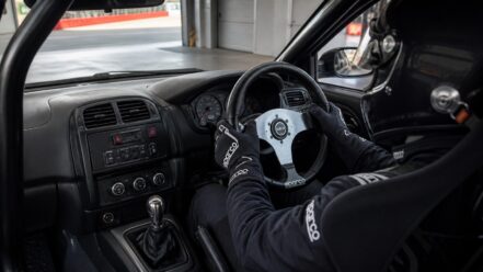 Right-hand-drive track car driver using a Sparco P222 flat-dish steering wheel