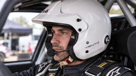 Rally driver wearing the white Stilo Venti4 Trophy Plus Rally helmet with peak and boom microphone