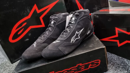 Black Alpinestars SP V2 race boots on their box in the GSM Performance showroom, with more Alpinestars boxes behind