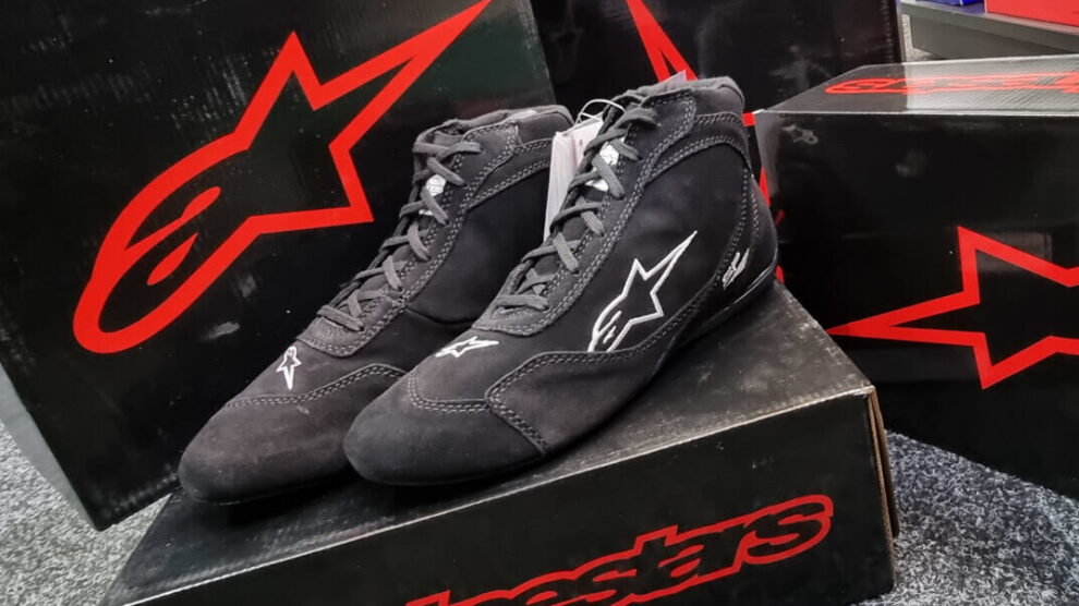 Black Alpinestars SP V2 race boots on their box in the GSM Performance showroom, with more Alpinestars boxes behind