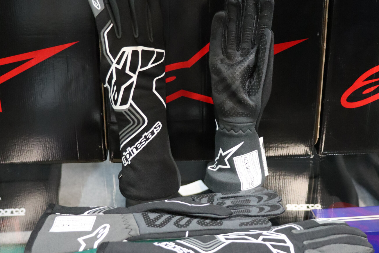 Black Alpinestars Tech 1 Race V4 gloves on display in front of Alpinestars boxes in the GSM Performance showroom