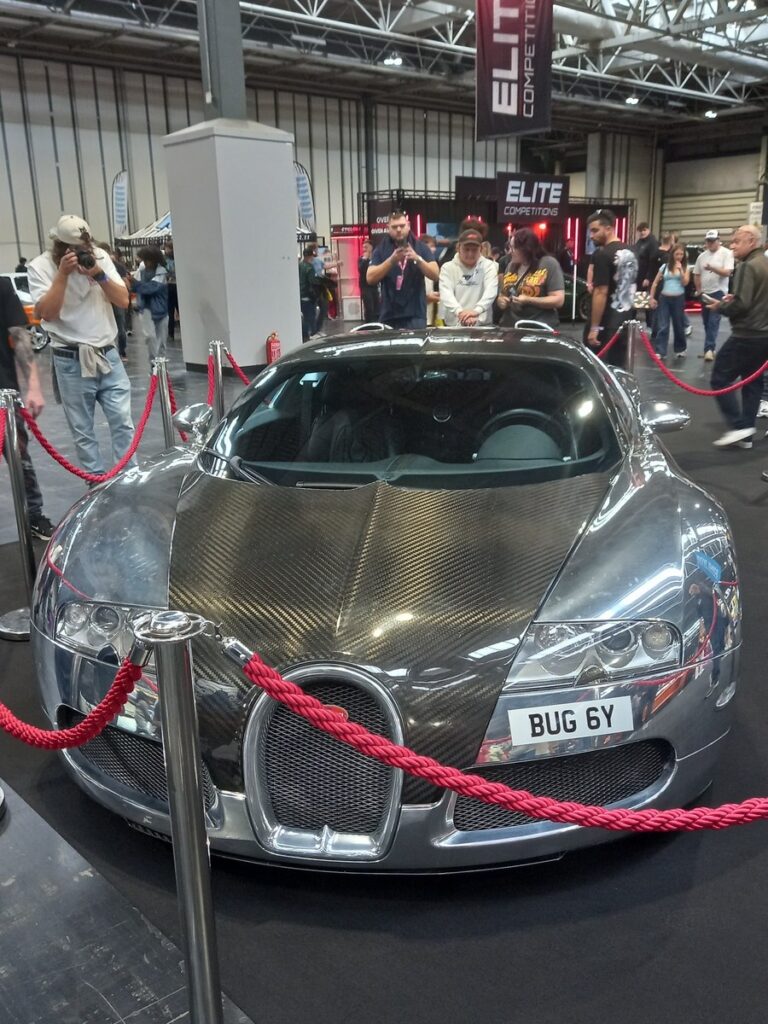 Polished aluminium and exposed carbon Bugatti Veyron seen head on behind red ropes at Gravity Show 2026