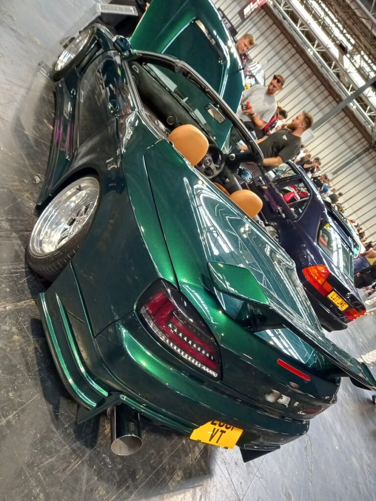 Deep green wide-body Nissan Silvia S15 with a large rear wing, polished deep dish wheels and tan bucket seats at Gravity Show 2026