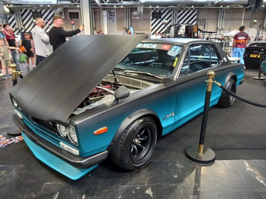 Hakosuka style Nissan Skyline GT-R in teal with a matte black bonnet raised, on black Watanabe style wheels