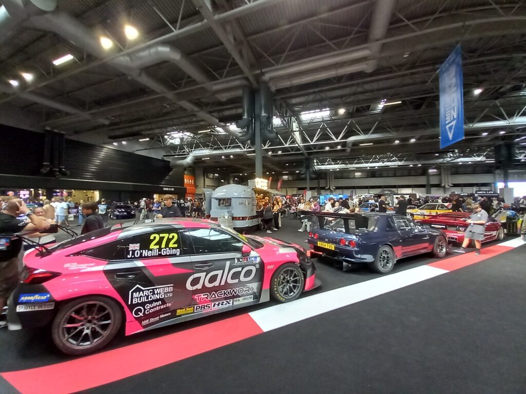 Pink and black TCR UK Honda Civic Type R number 272 beside a dark blue Nissan Skyline with a big rear wing on the motorsport display
