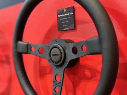 A MOMO Prototipo Black Edition steering wheel on the red display wall of the MOMO stand