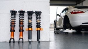 A MOTON 1-way Clubracer kit stood against a pit garage wall with a Porsche Cayman on a jack